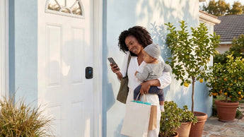 Busy mother holding a baby and shopping bags while using her phone to unlock a SAWHERO smart lock remotely.